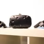 An HTC vive VR headset with the controllers sitting on top of a shelf