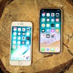 Two iPhones sitting face up on a tree stump