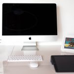 image of workstation, with an iMac, a keyboard, a mouse, a plant, and a picture frame