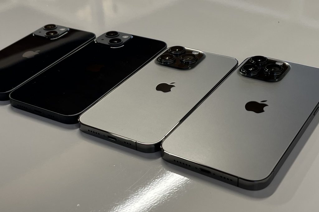 iPhone 13 series devices laying facedown on a white surface
