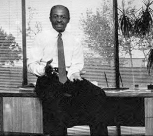 Roy L. Clay, a Black leader in tech history, sitting on a desk in a black and white photo