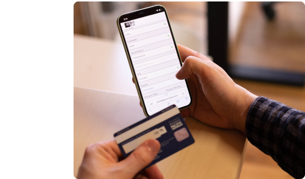Tester holding a credit card in front of a mobile device. On the device, the tester is entering their card details into a form on an e-commerce website.