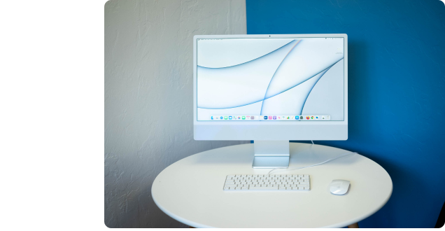 An M1 iMac open to the desktop screen, set up on a circular table.