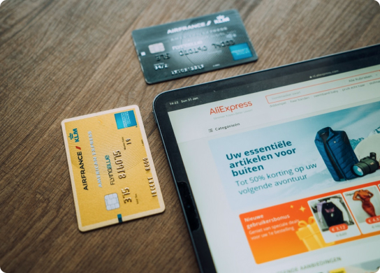 Tablet device pictured next to two credit cards. On the tablet, the website 'AliExpress' is loaded.