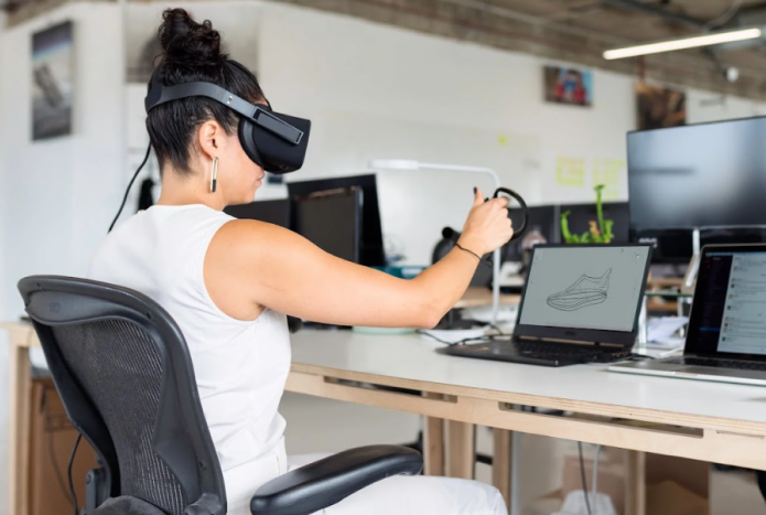 Woman wearing VR headset working at her desk on a software project.