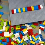 A photo of Jesus's hands touching a pile of LEGO Braille Bricks. He spelled out #accessibility on the gray baseplate.